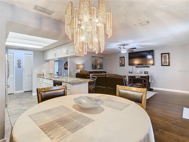 dining area with ceiling fan, sink, a textured ceiling, and light hardwood / wood-style floors