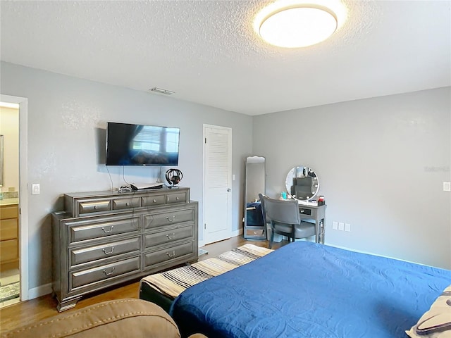 bedroom featuring a textured ceiling, hardwood / wood-style flooring, and ensuite bath