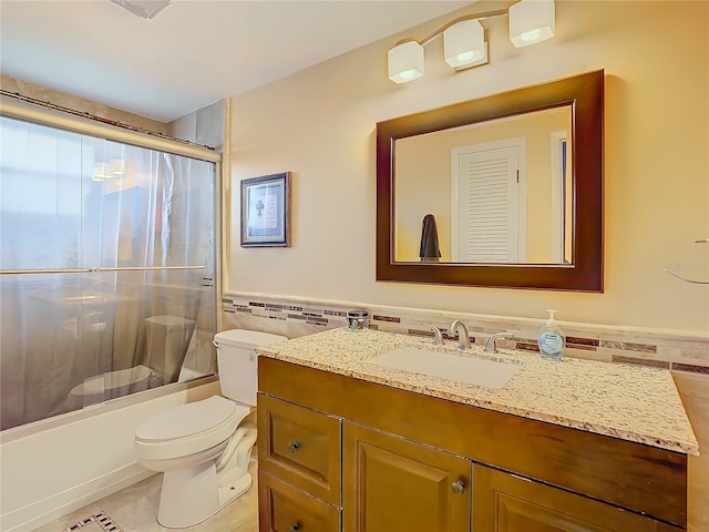 full bathroom with toilet, tile walls, tile patterned floors, vanity, and shower / bath combination with glass door