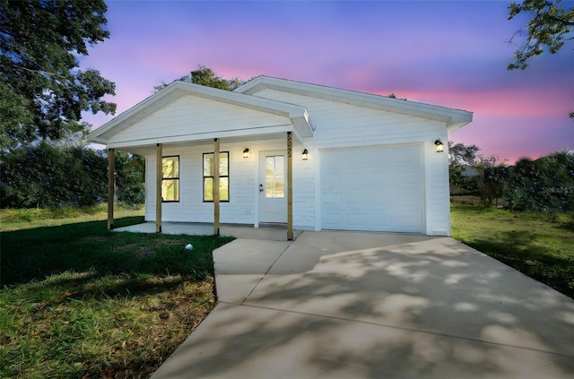 view of front of property with a garage, a lawn, and covered porch