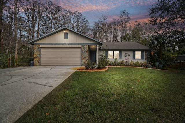 ranch-style home with a garage and a lawn