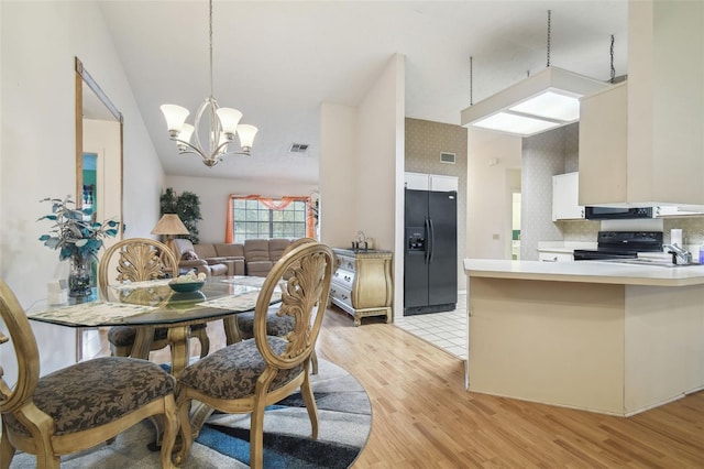 dining area with light wood-type flooring, an inviting chandelier, and sink