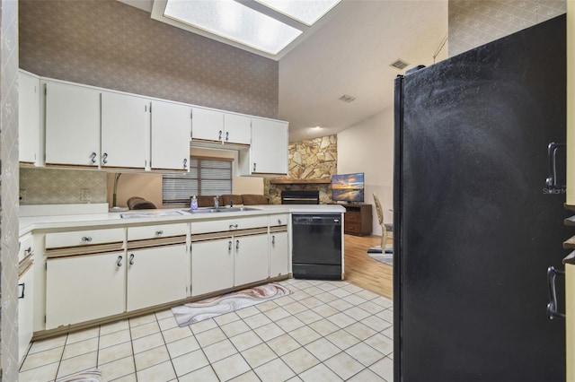 kitchen featuring white cabinets, a skylight, black dishwasher, and sink