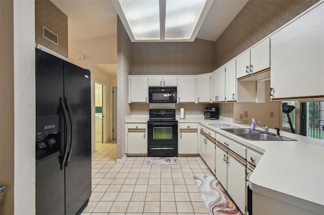 kitchen with black appliances, white cabinetry, sink, vaulted ceiling, and light tile patterned floors