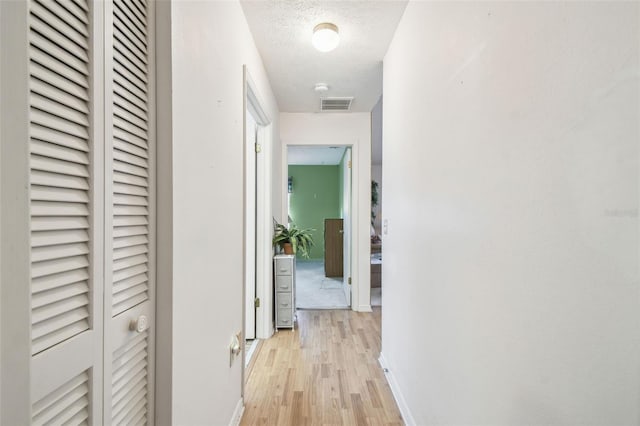 hall featuring a textured ceiling and light hardwood / wood-style flooring