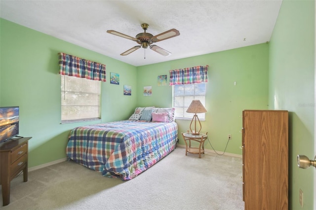 bedroom with ceiling fan, light colored carpet, and a textured ceiling