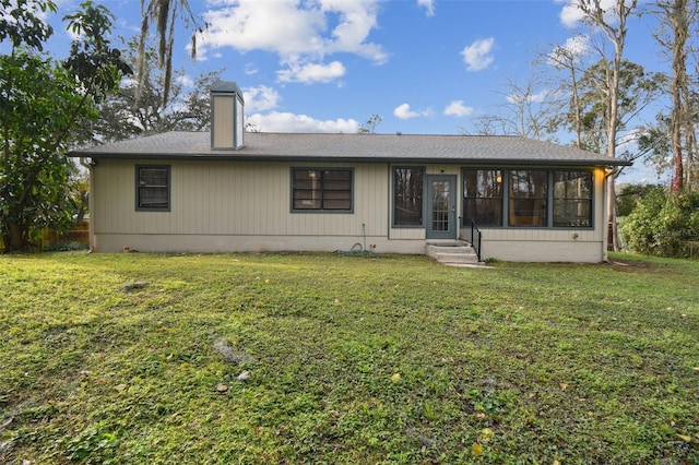 back of property featuring a sunroom and a lawn