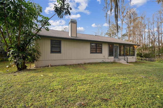 rear view of property featuring a lawn and a sunroom