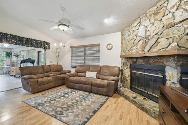 living room with lofted ceiling, hardwood / wood-style flooring, ceiling fan, a fireplace, and a textured ceiling