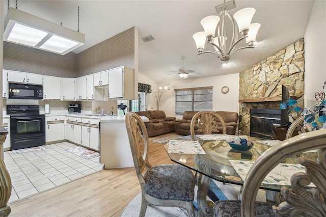 dining area featuring lofted ceiling, a stone fireplace, sink, light wood-type flooring, and ceiling fan with notable chandelier