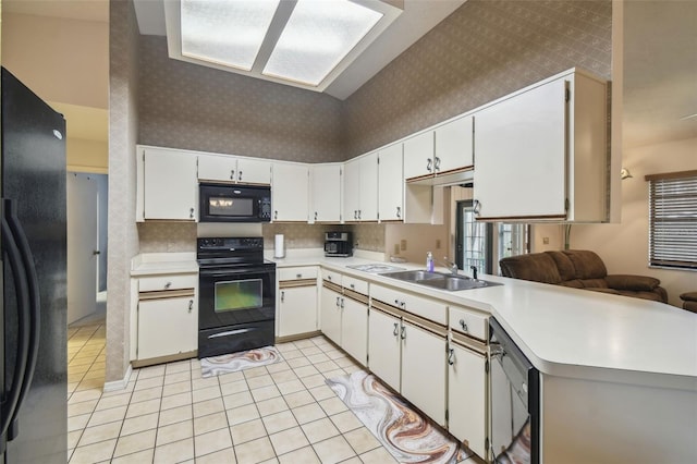 kitchen with sink, black appliances, light tile patterned floors, kitchen peninsula, and white cabinets