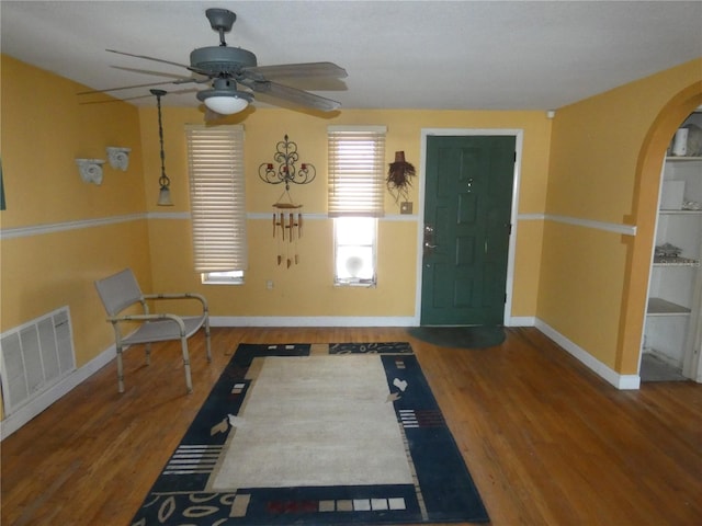 entryway with visible vents, arched walkways, baseboards, and wood finished floors