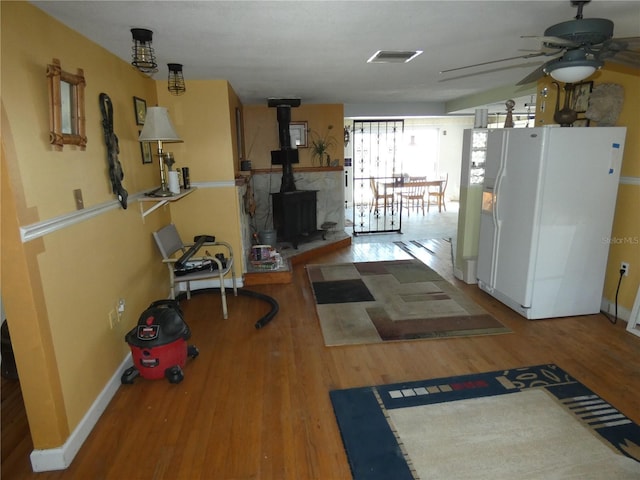 exercise area with visible vents, a wood stove, a ceiling fan, and wood finished floors