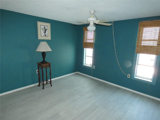 empty room with plenty of natural light, wood finished floors, and baseboards