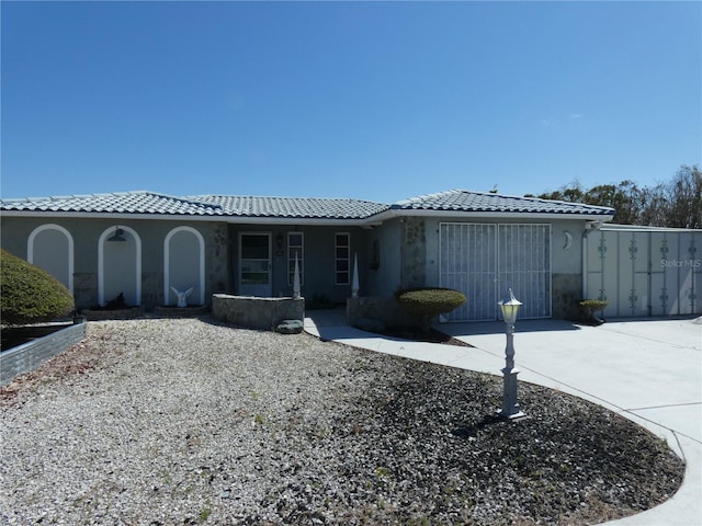 view of front of house featuring stucco siding, a tiled roof, and driveway