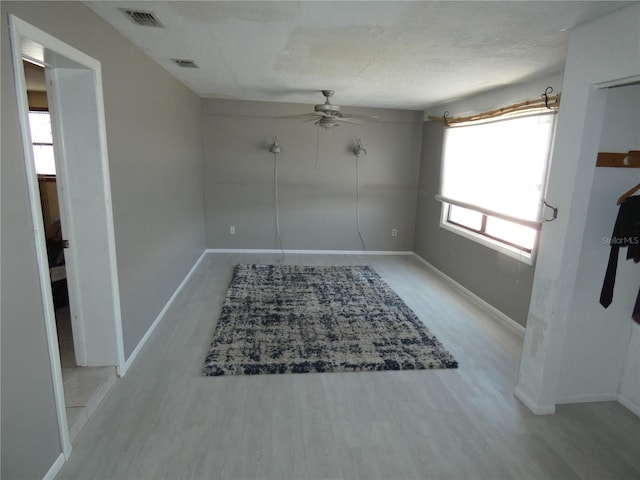 empty room featuring ceiling fan, wood finished floors, visible vents, and baseboards