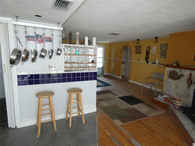 bar with tile patterned flooring, visible vents, and arched walkways