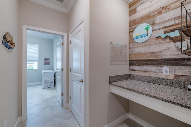 hallway featuring light tile patterned flooring, ornamental molding, and wood walls