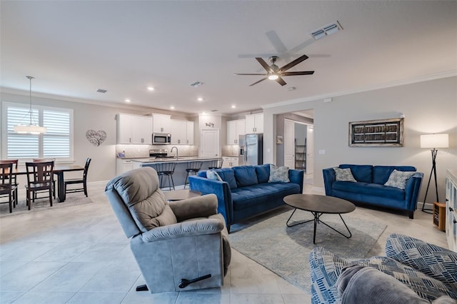 living room featuring crown molding, ceiling fan, light tile patterned flooring, and sink