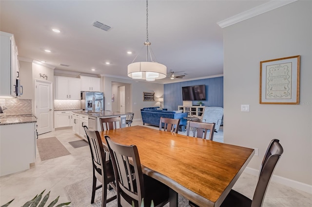 tiled dining area featuring sink and crown molding