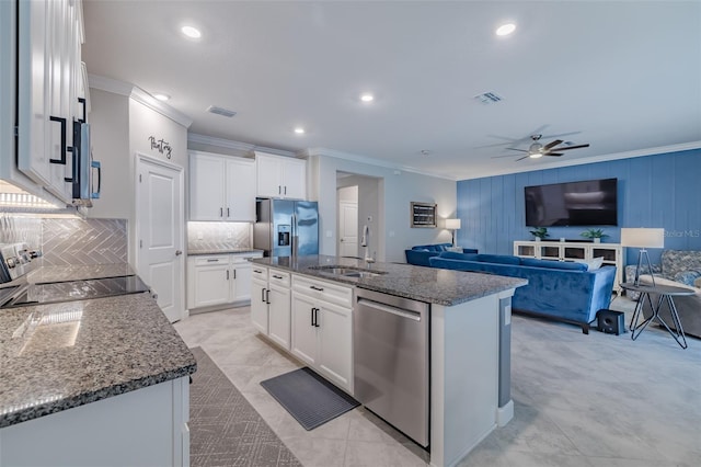 kitchen with stainless steel appliances, an island with sink, sink, and white cabinets