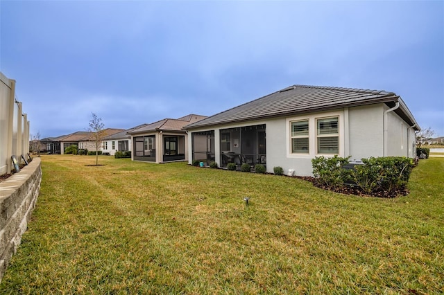 rear view of property with a sunroom and a lawn