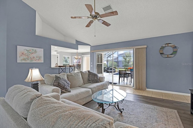 living room with hardwood / wood-style flooring, high vaulted ceiling, ceiling fan with notable chandelier, and a textured ceiling