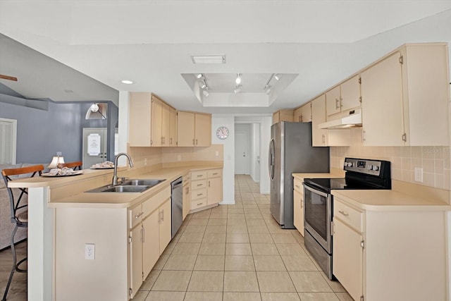 kitchen with sink, a breakfast bar area, stainless steel appliances, kitchen peninsula, and a raised ceiling