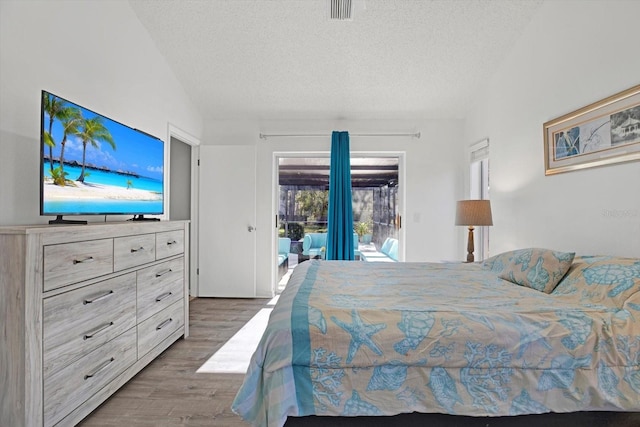 bedroom featuring lofted ceiling, dark hardwood / wood-style floors, access to outside, and a textured ceiling