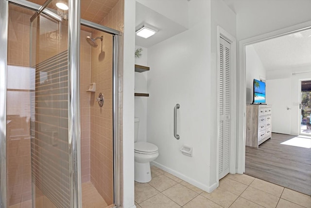 bathroom with tile patterned flooring, a shower with door, and toilet