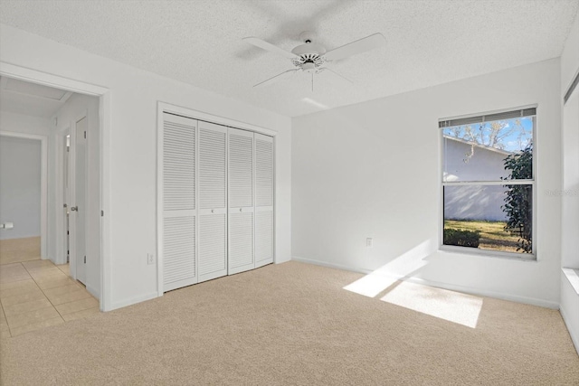 unfurnished bedroom with light carpet, a textured ceiling, ceiling fan, and a closet