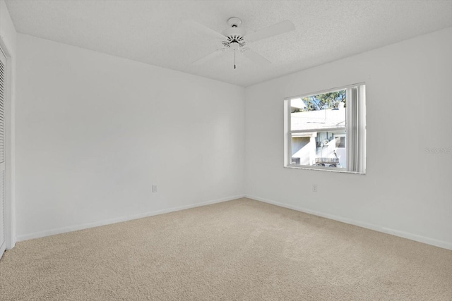 carpeted empty room featuring ceiling fan and a textured ceiling