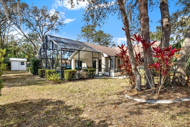 rear view of property featuring a storage shed, glass enclosure, and a lawn