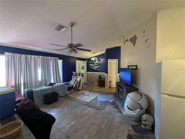 bedroom with white fridge, ceiling fan, a textured ceiling, and vaulted ceiling