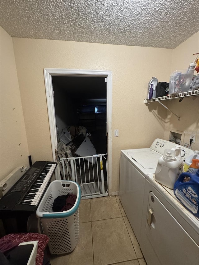 washroom featuring light tile patterned floors, a textured ceiling, and washer and clothes dryer