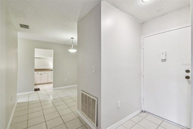 foyer entrance with a textured ceiling and light tile patterned floors