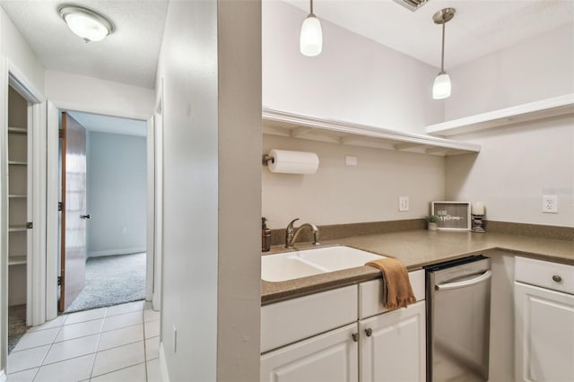 kitchen with a textured ceiling, decorative light fixtures, white cabinetry, sink, and light tile patterned floors