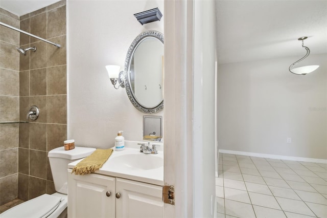 bathroom featuring toilet, vanity, tiled shower, and tile patterned flooring