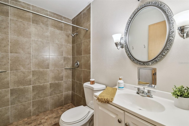 bathroom featuring toilet, vanity, and a tile shower