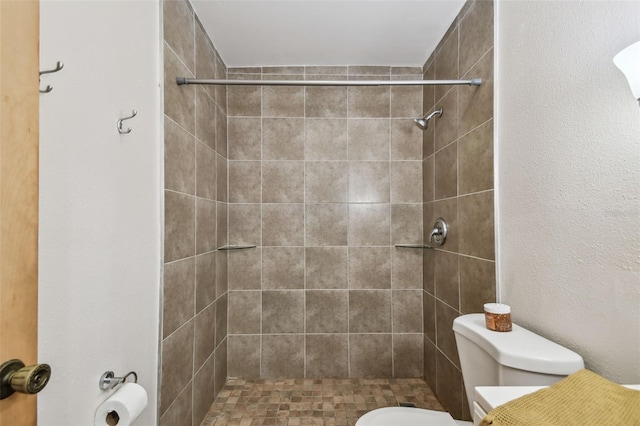 bathroom featuring toilet and a tile shower