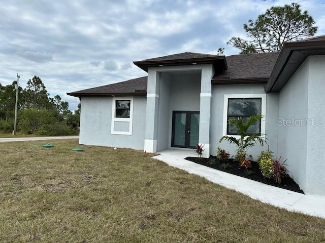 rear view of property with a lawn and french doors