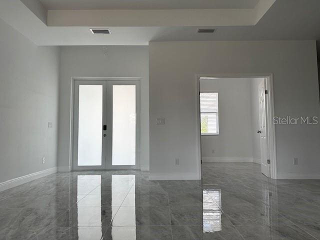 empty room with a raised ceiling and french doors