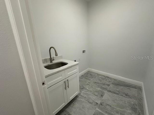 clothes washing area with sink, washer hookup, and cabinets