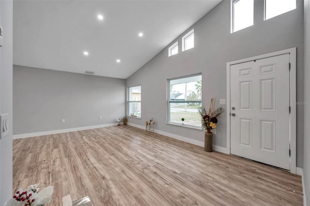 foyer featuring light wood-type flooring and high vaulted ceiling