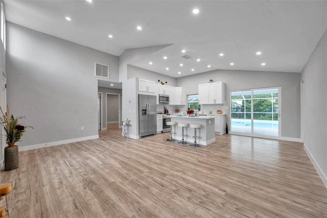 kitchen featuring a center island, white cabinetry, stainless steel appliances, light hardwood / wood-style flooring, and a breakfast bar area