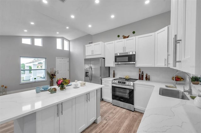 kitchen with sink, light stone counters, stainless steel appliances, and white cabinetry