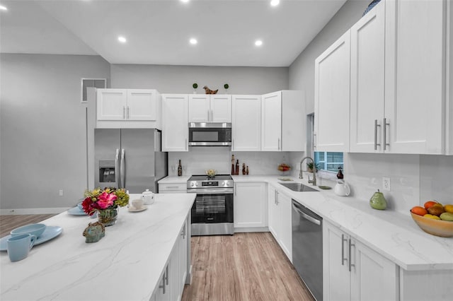 kitchen featuring light hardwood / wood-style floors, appliances with stainless steel finishes, white cabinets, light stone counters, and sink