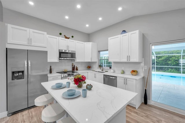 kitchen with plenty of natural light, white cabinets, stainless steel appliances, and tasteful backsplash