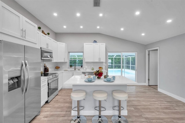 kitchen featuring white cabinets, a breakfast bar, stainless steel appliances, and a center island