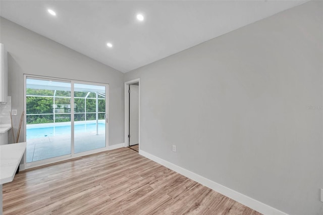 spare room with light hardwood / wood-style floors and lofted ceiling